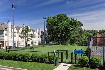 A blue sign on a black fence in front of a green bush.